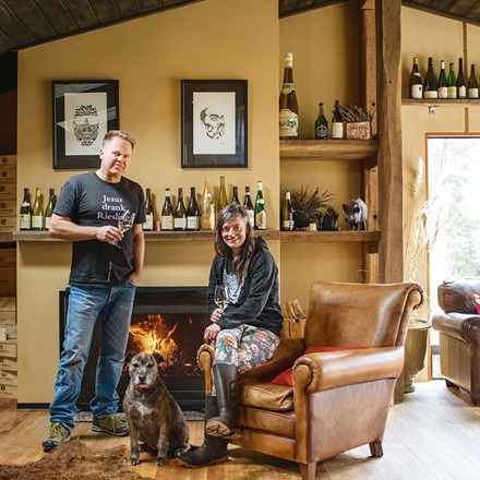 Duncan Forsyth and Anna Riederer infront of a fireplace with a dog