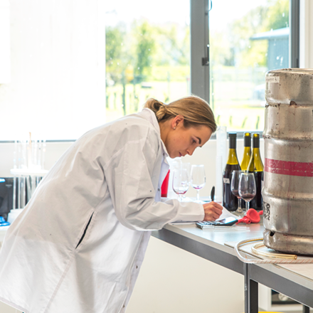 Girl in lab coat with wine bottles