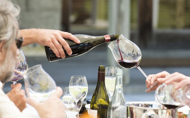 A bottle pouring pinot noir into a glass.