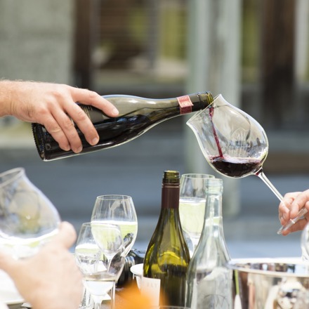 A bottle pouring pinot noir into a glass.